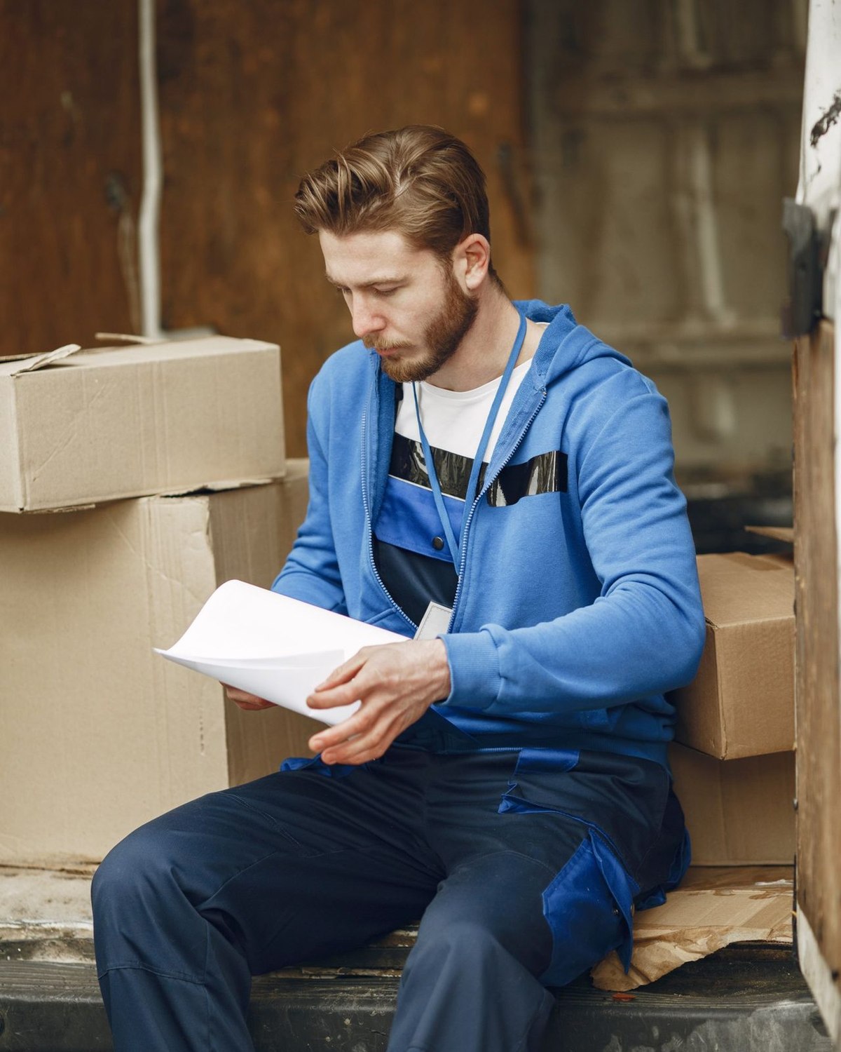 A delivery worker checking paperwork beside stacked boxes
