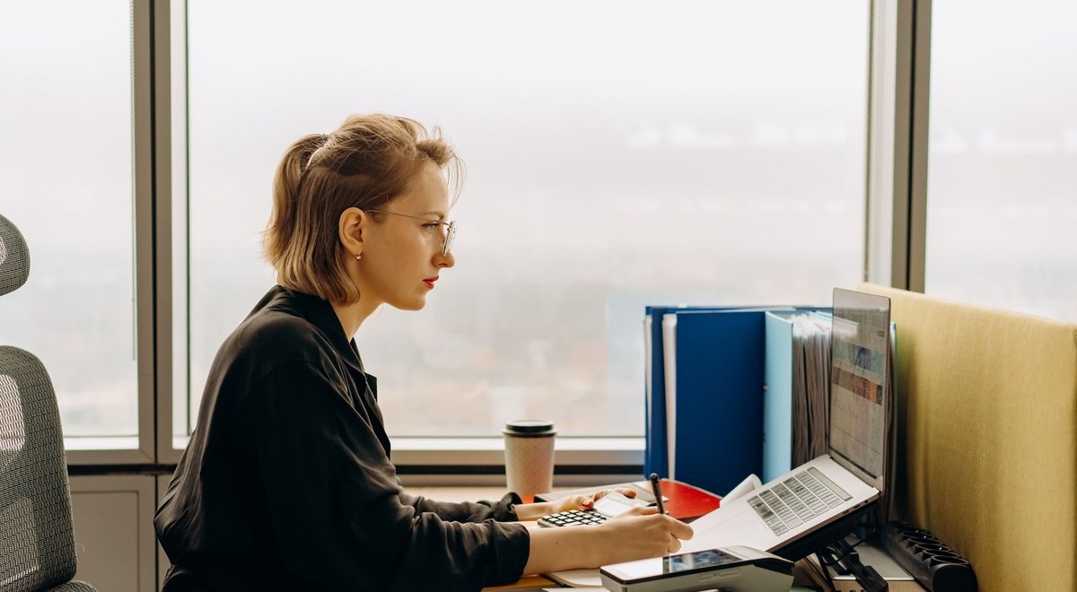 An office worker reviewing documents beside a laptop